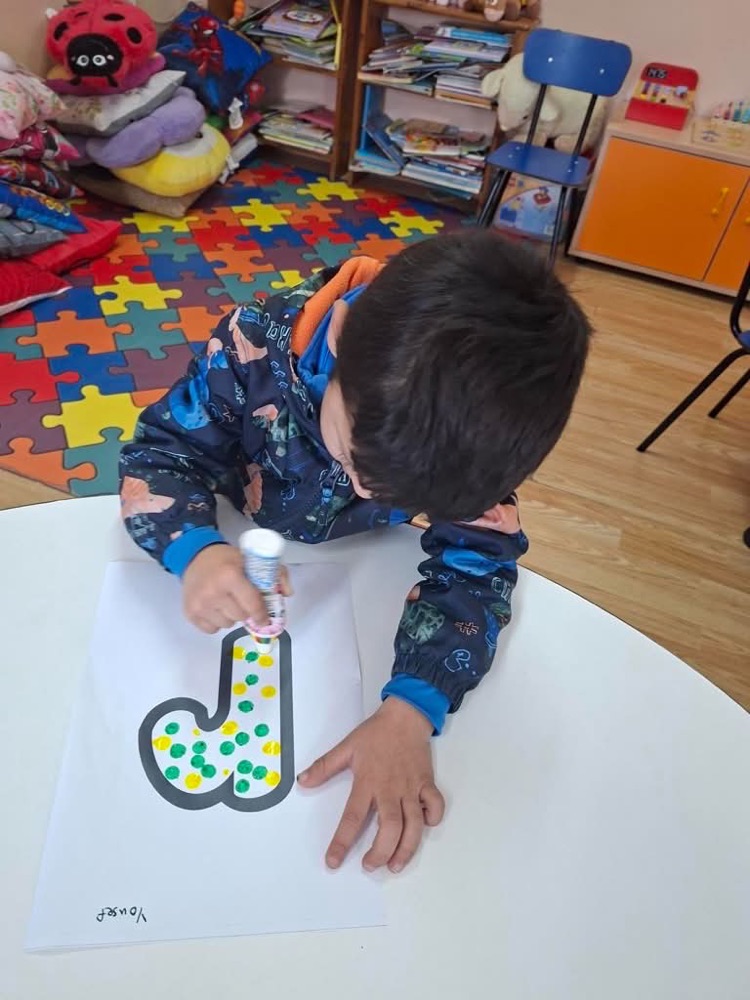 A young child decorating a large cut-out letter