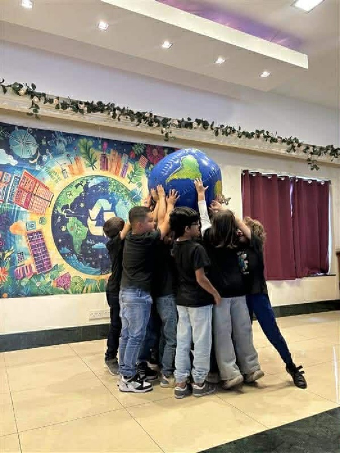 Pupils lifting a large inflatable globe in front of a painted world mural