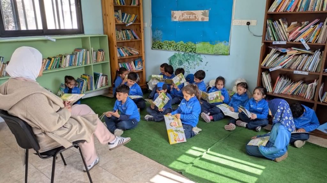 Kindergarten children sitting on the carpet reading picture books in the school library